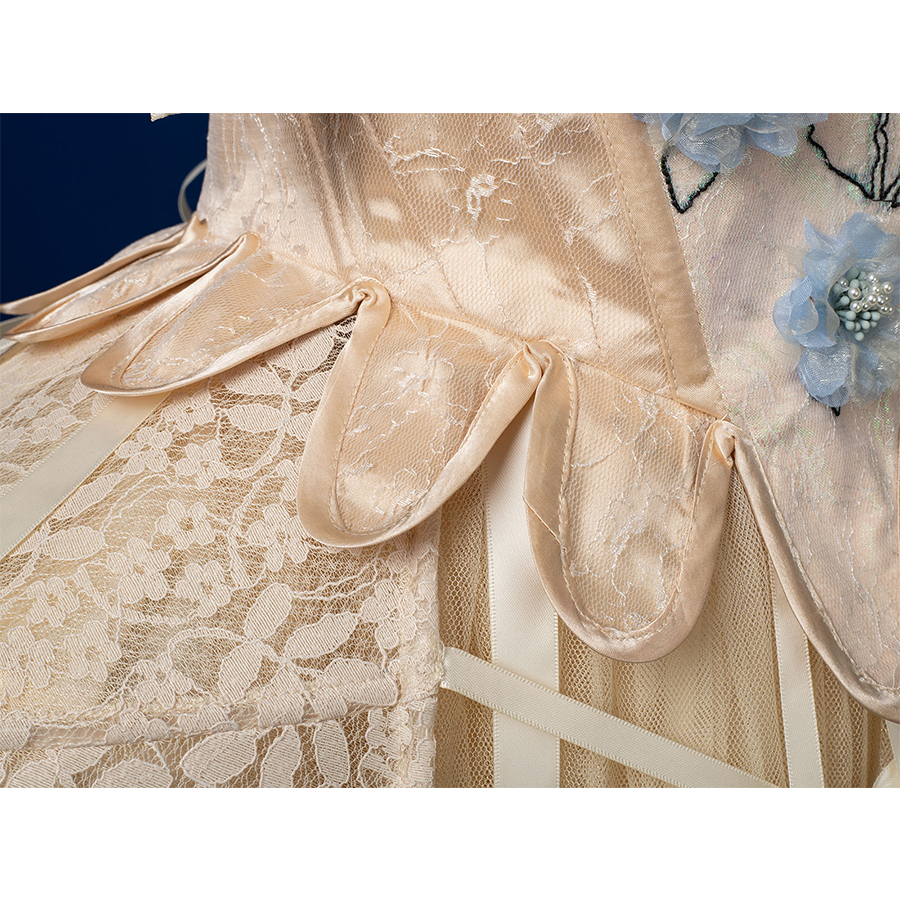 Enid Sinclair Gala dress waist close-up with satin ribbon bows, lace trim, blue floral embroidery, layered tulle texture