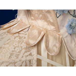 Enid Sinclair Gala dress waist close-up with satin ribbon bows, lace trim, blue floral embroidery, layered tulle texture