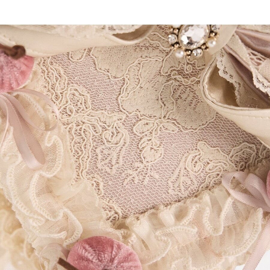 Close-up of embroidered lace, ruffled trim, satin bow layers, and cherry details