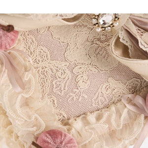 Close-up of embroidered lace, ruffled trim, satin bow layers, and cherry details