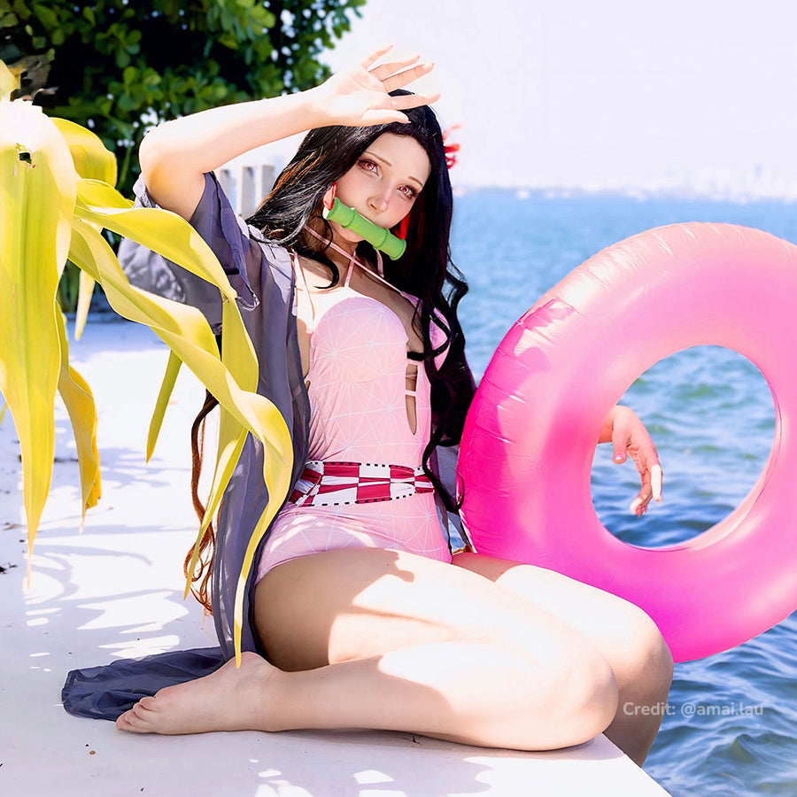 Nezuko cosplay swimsuit layers a pink one-piece beneath sheer black sleeves and red waist trim.