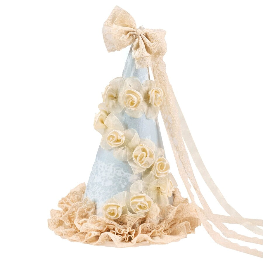 Pointed cream hat flat lay with pale blue panels, rose trim, lace base, and bow streamers