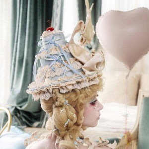 Side view of the cream pointed hat showing lace trim and ribbon streamers