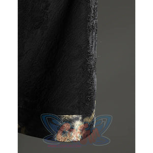 Close-up of the Fire Keeper cape hem showing the black textured fabric and softly reflective metallic edge trim.