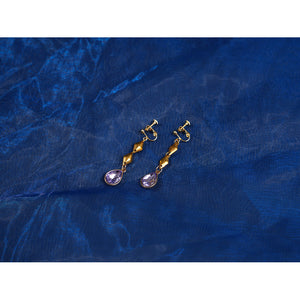 Genshin Impact Snezhnaya Odette cosplay earrings flat lay pairs gold-tone drops with violet accents.