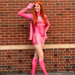 Invincible Atom Eve cosplay costume standing view sets a pink jumpsuit below the sheer shawl and knee socks.