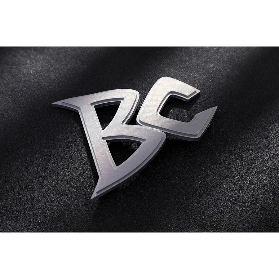 Marvel Rivals Black Cat Felicia Hardy cosplay BC logo detail rests in silver-tone metal on black fabric.