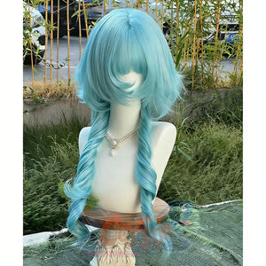Peacock teal blue lolita wig with long braided pigtails shown on a mannequin outdoors, featuring fluffy bangs and wavy texture with bamboo plants in the background