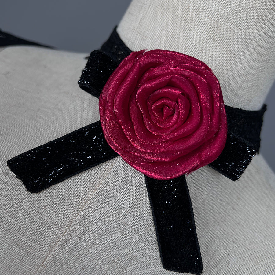 Wuthering Waves Phrolova cosplay rose collar close-up frames red petals over black lace trim.