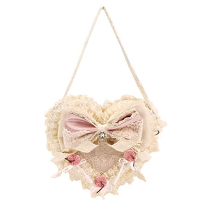 Pink heart handbag flat lay on a white background with lace ruffles, satin bow, and cherry accents