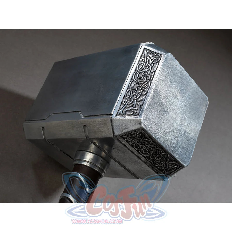 Thor cosplay hammer depicts a heavy metallic head with ornate engraved patterns and a dark wrapped handle structure.