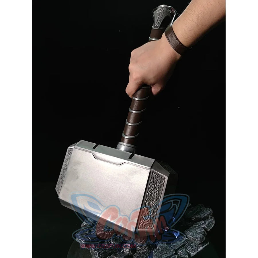 Thor cosplay hammer centers a rectangular metal block with ornate side carvings beneath a gripped cylindrical handle.