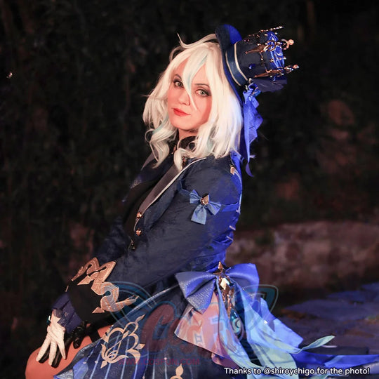 Genshin Impact Furina cosplay tailcoat layers gold embroidery over blue brocade beside a crown-topped mini top hat.