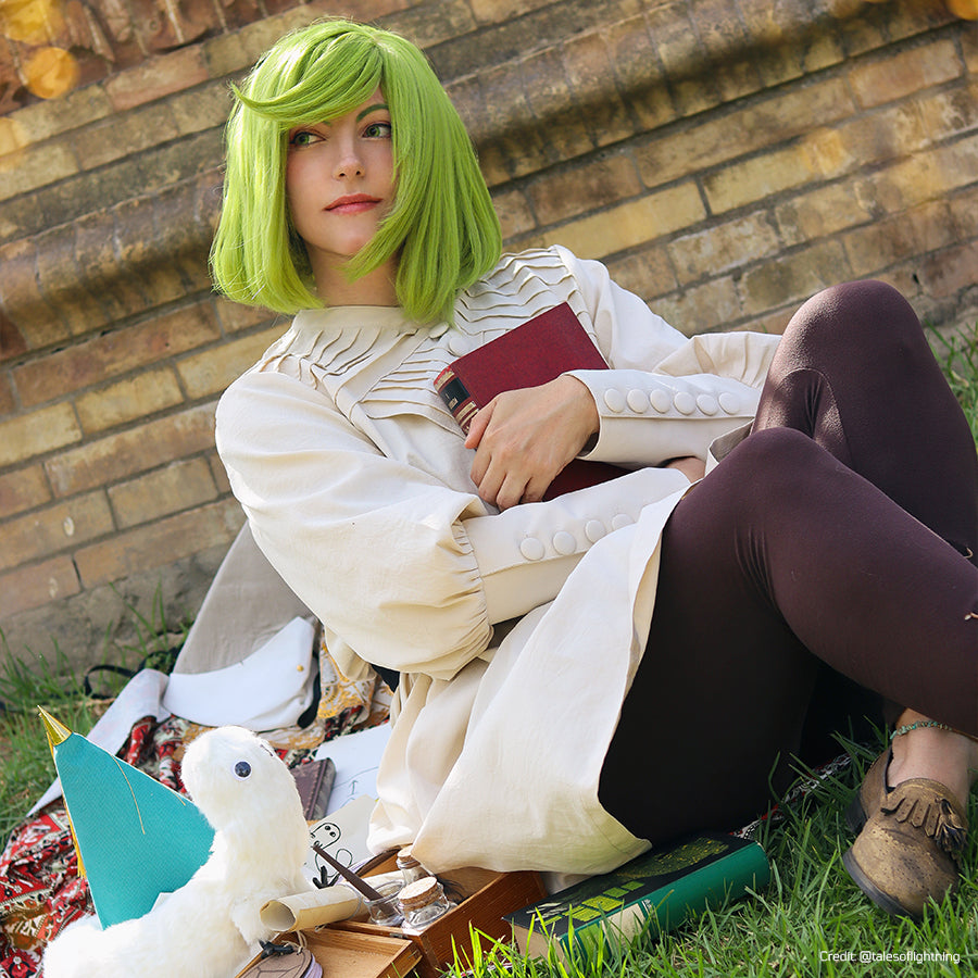 Witch Hat Atelier Coco cosplay costume seated view reveals the cream robe and dark leggings without the teal cloak.