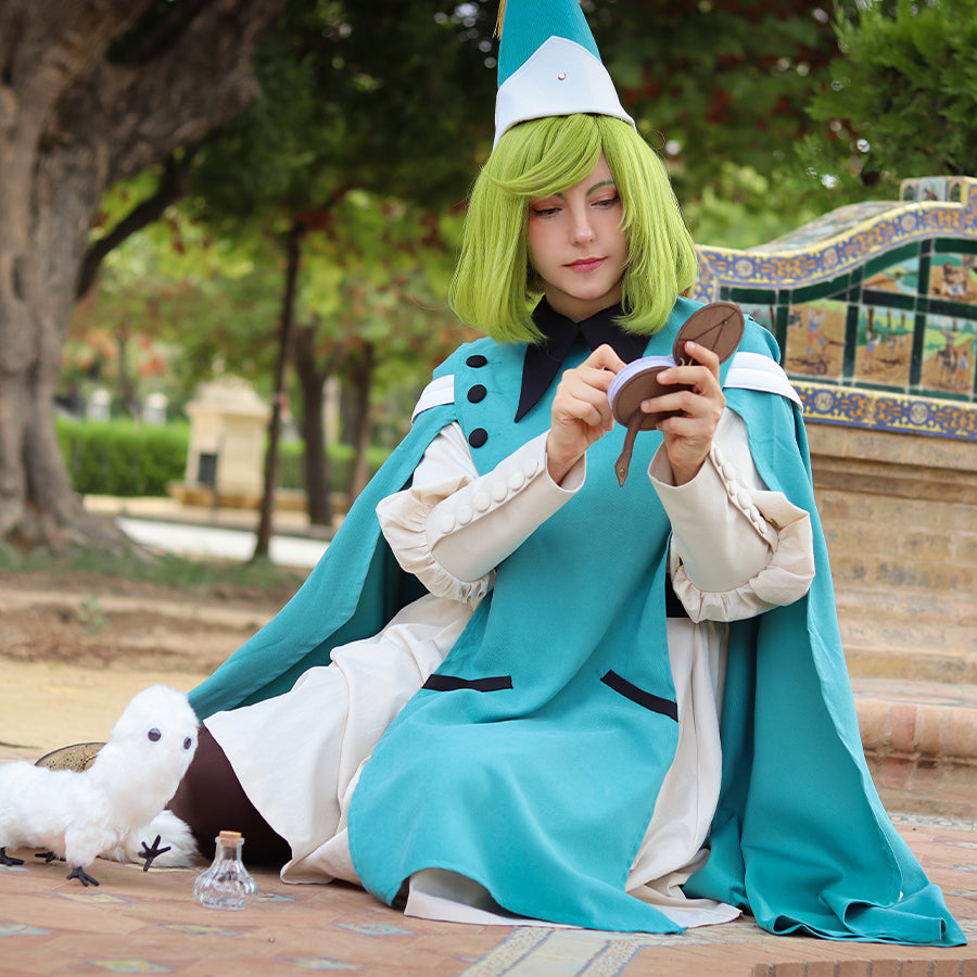 COSFUN Witch Hat Atelier Coco cosplay costume seated view frames a teal cloak around the cream apprentice robe.