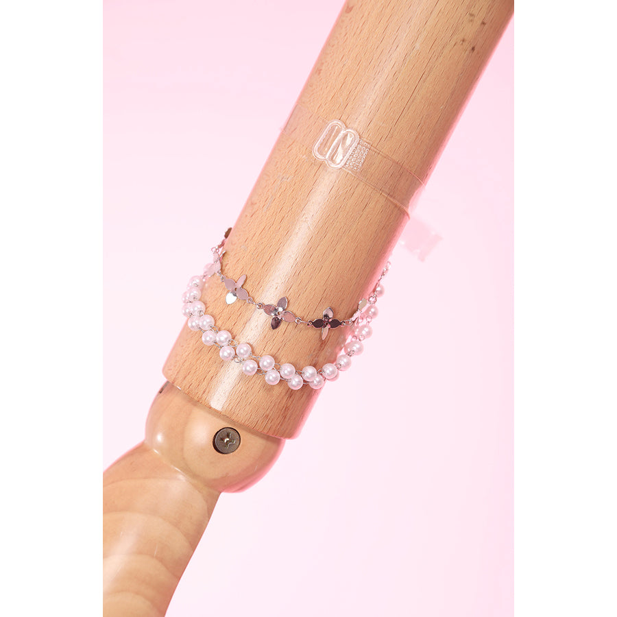 Wuthering Waves Aemeath cosplay arm chain detail drapes pearl-like beads and star charms beside a clear arm ring.