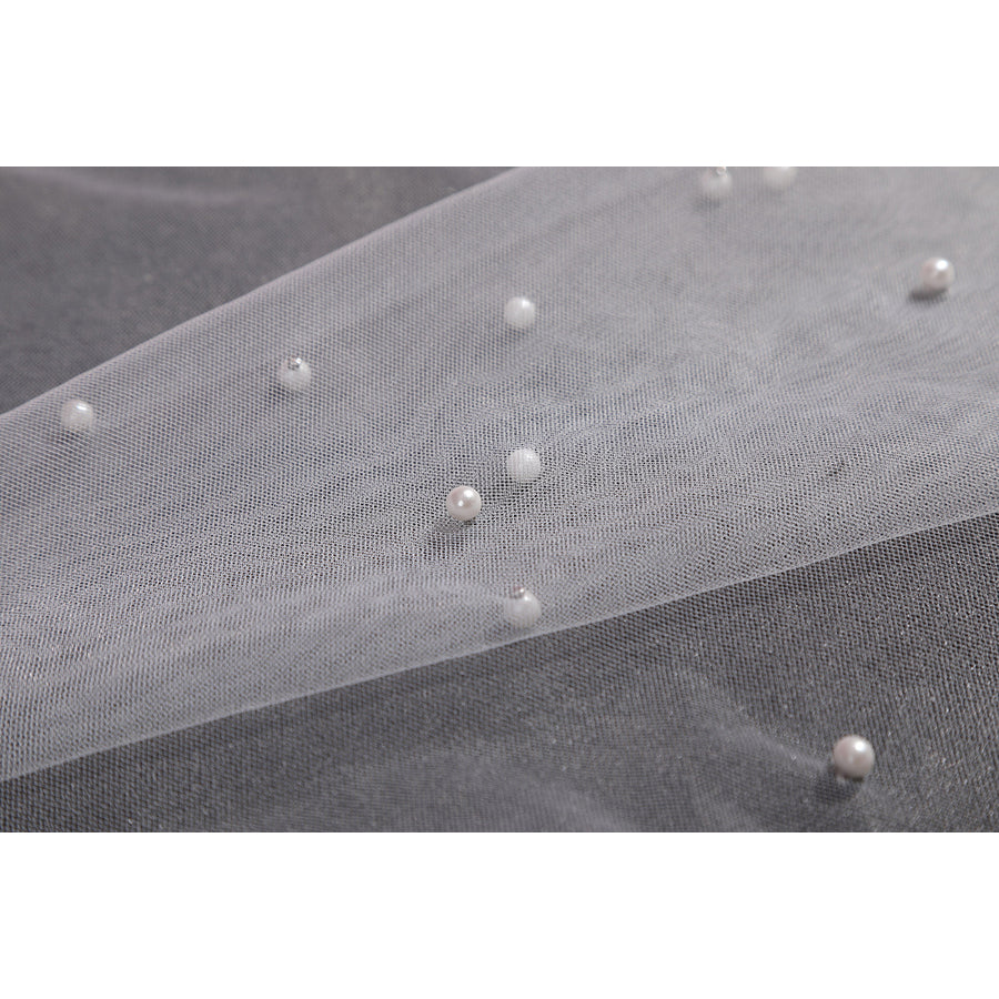Wuthering Waves Aemeath cosplay beaded mesh detail scatters pearl-like beads across sheer white fabric.